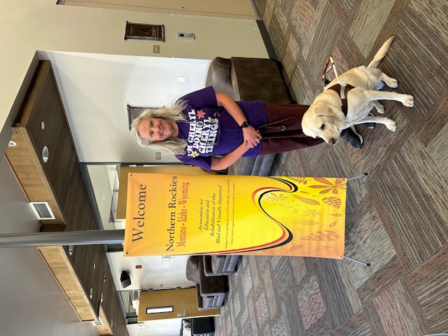 Cheryl standing in fron of the sign for the Association for Education and Rehabilitation of the Blind and Visually Impaired